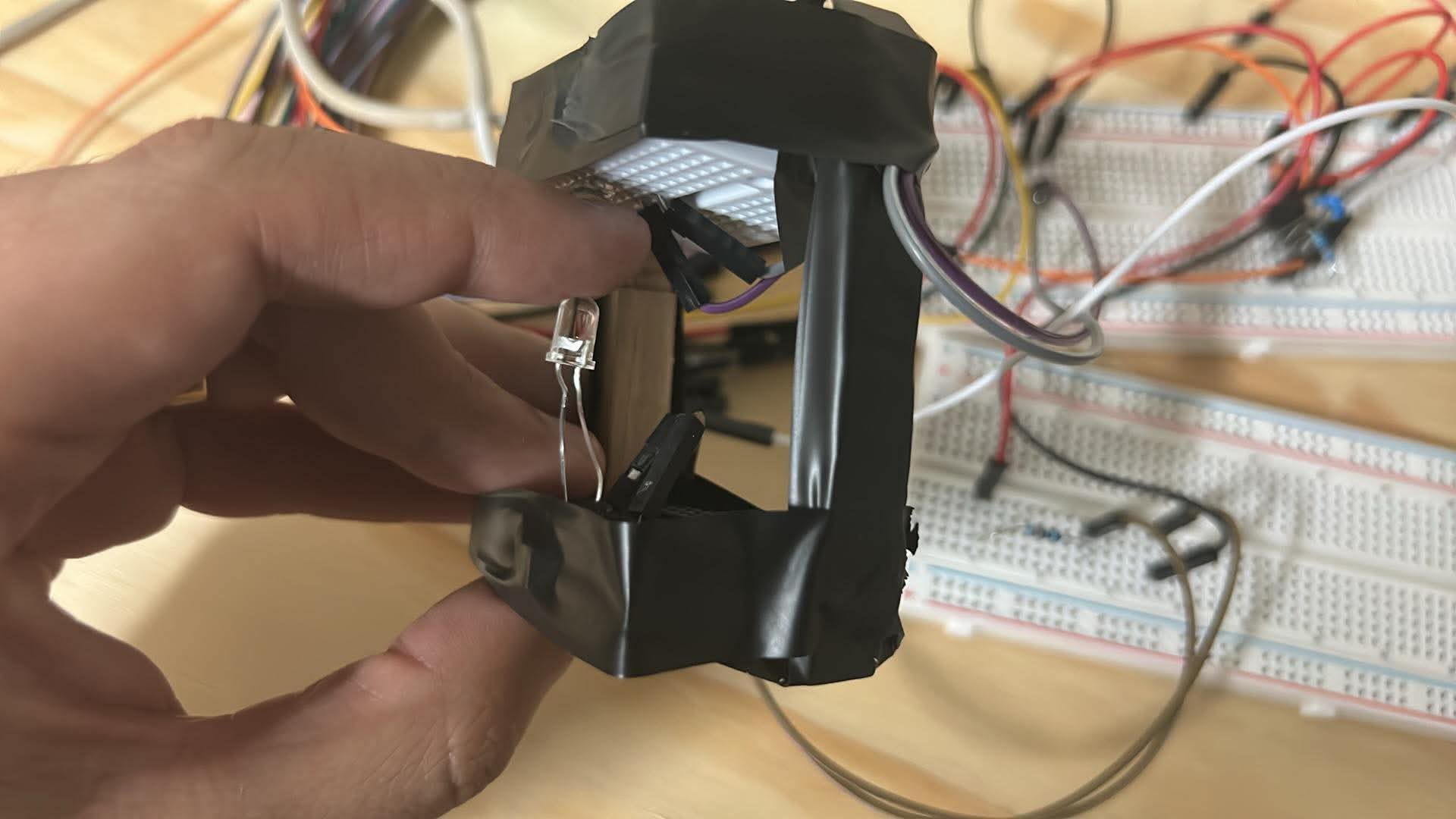 Close-up of the handmade fingertip sensor, with an optical component and wiring connected to breadboards